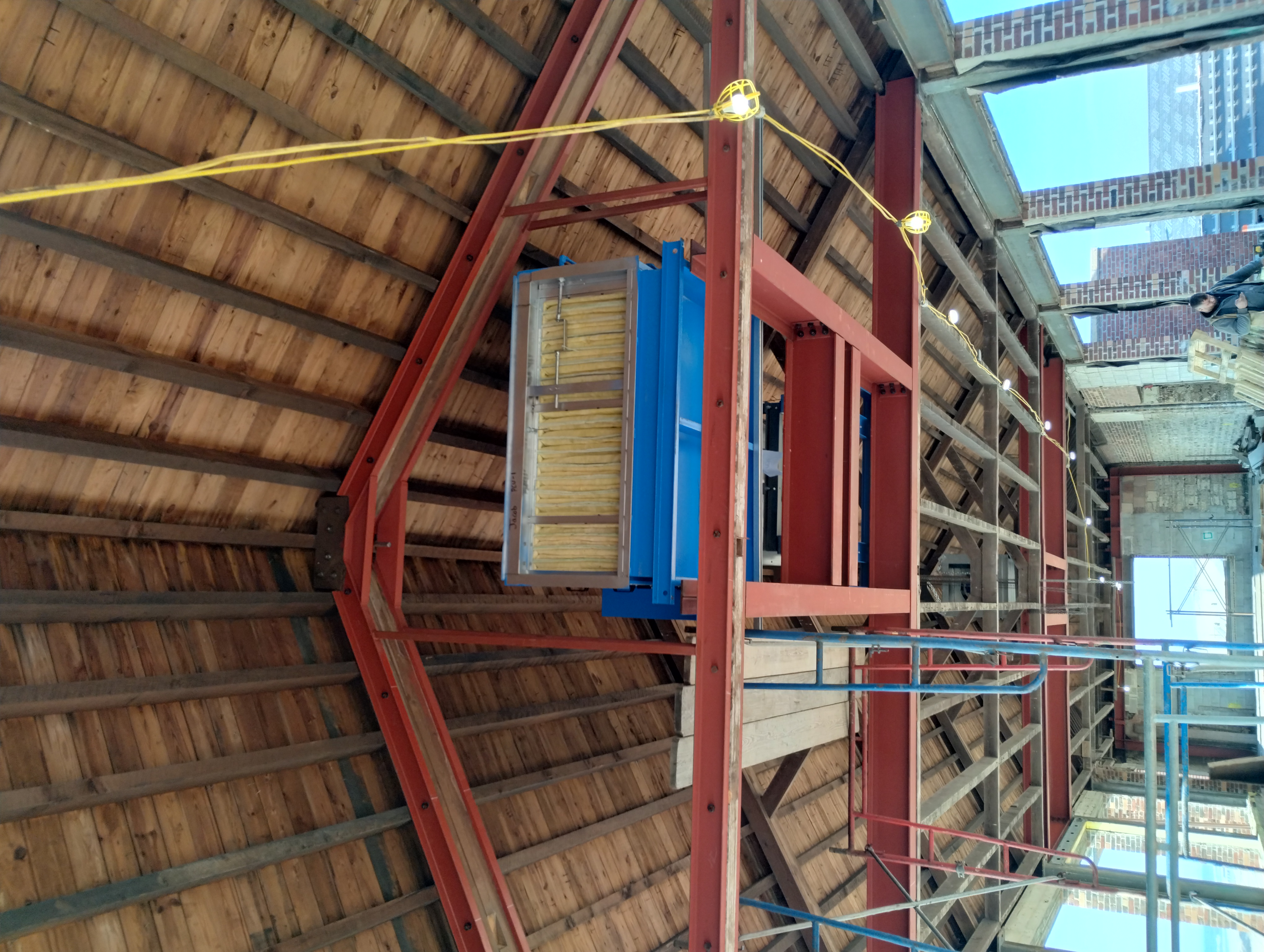 Red-primed steel framing supporting mechanical equipment below a timber roof