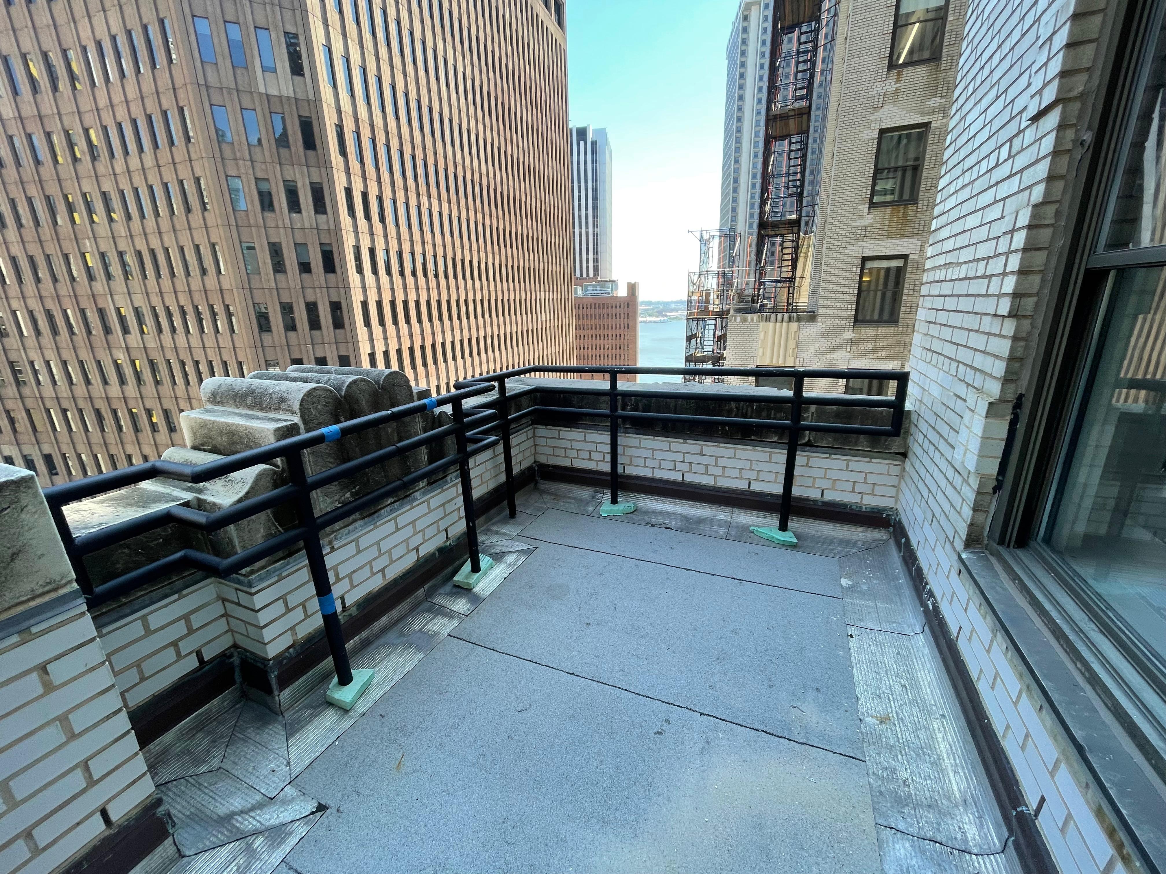 Black metal railings around a rooftop terrace beside brick parapets