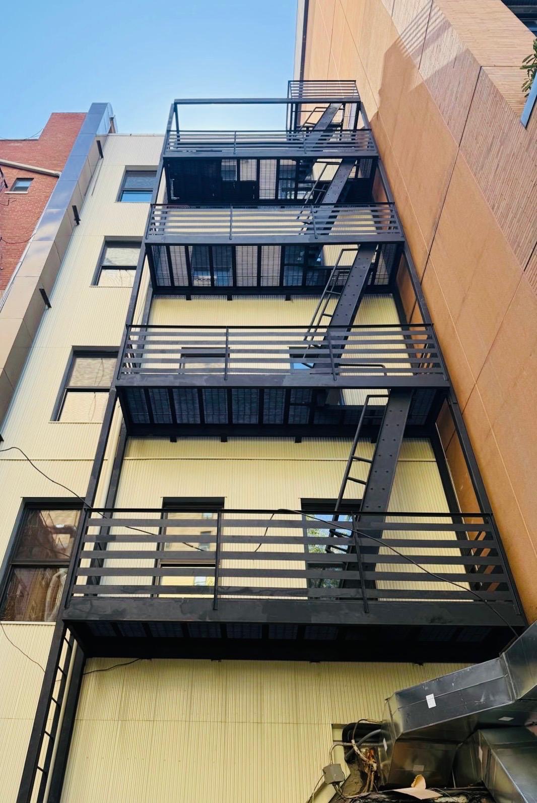 Exterior steel stairs connecting multiple grated landings with horizontal railings