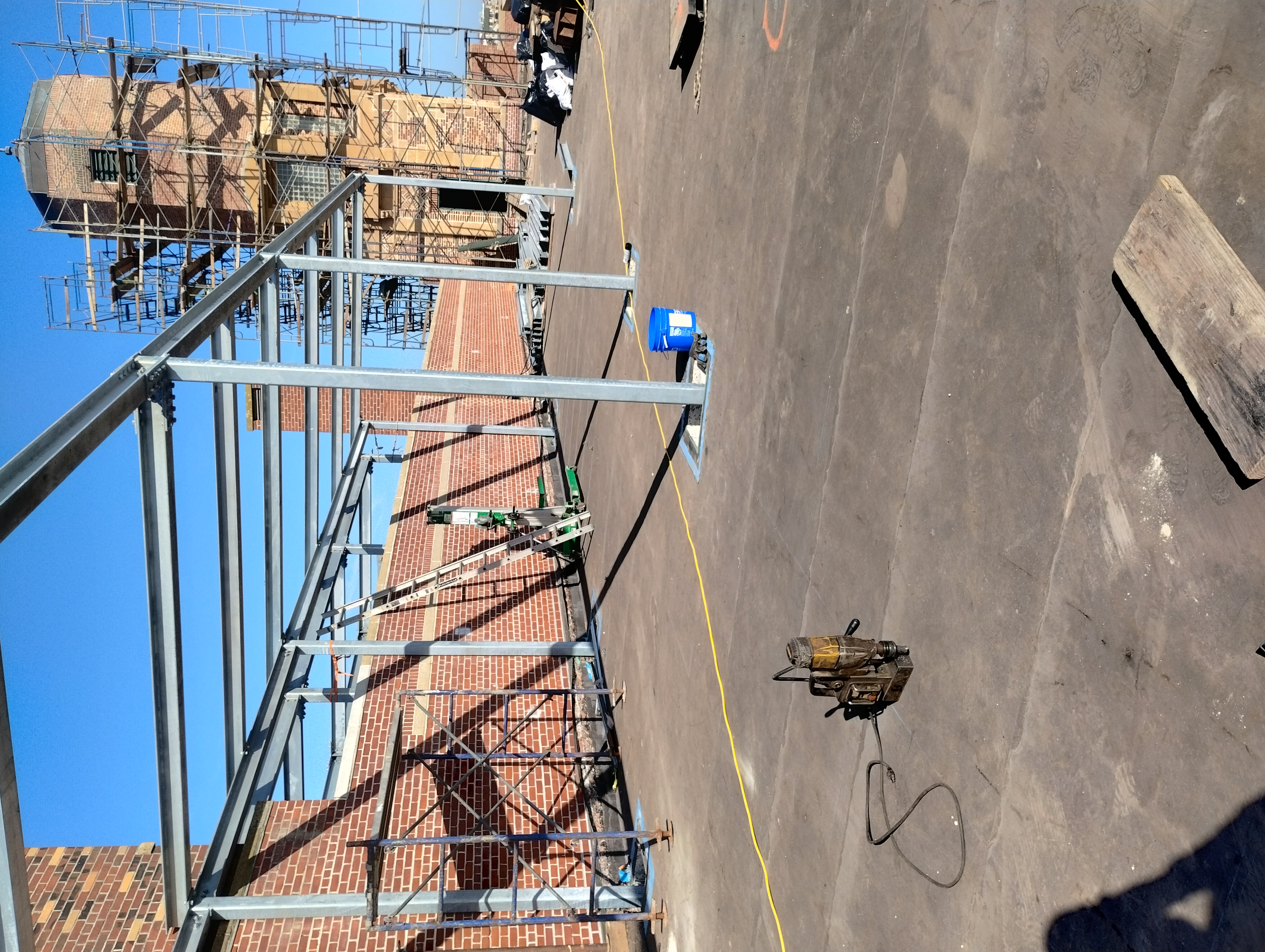 Rooftop steel columns and overhead beams beside a brick building