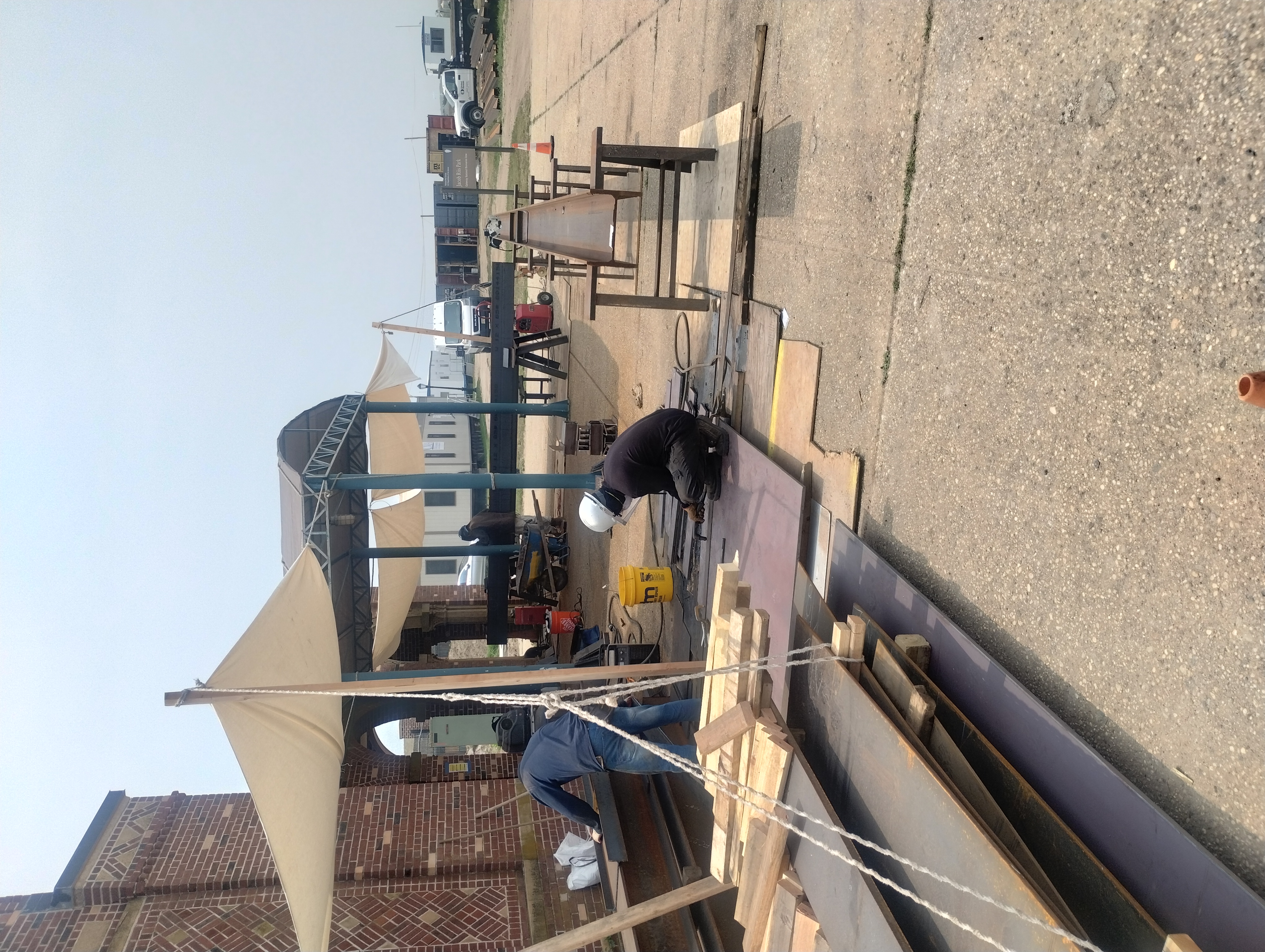Crew working on steel plates and beams at an outdoor work area