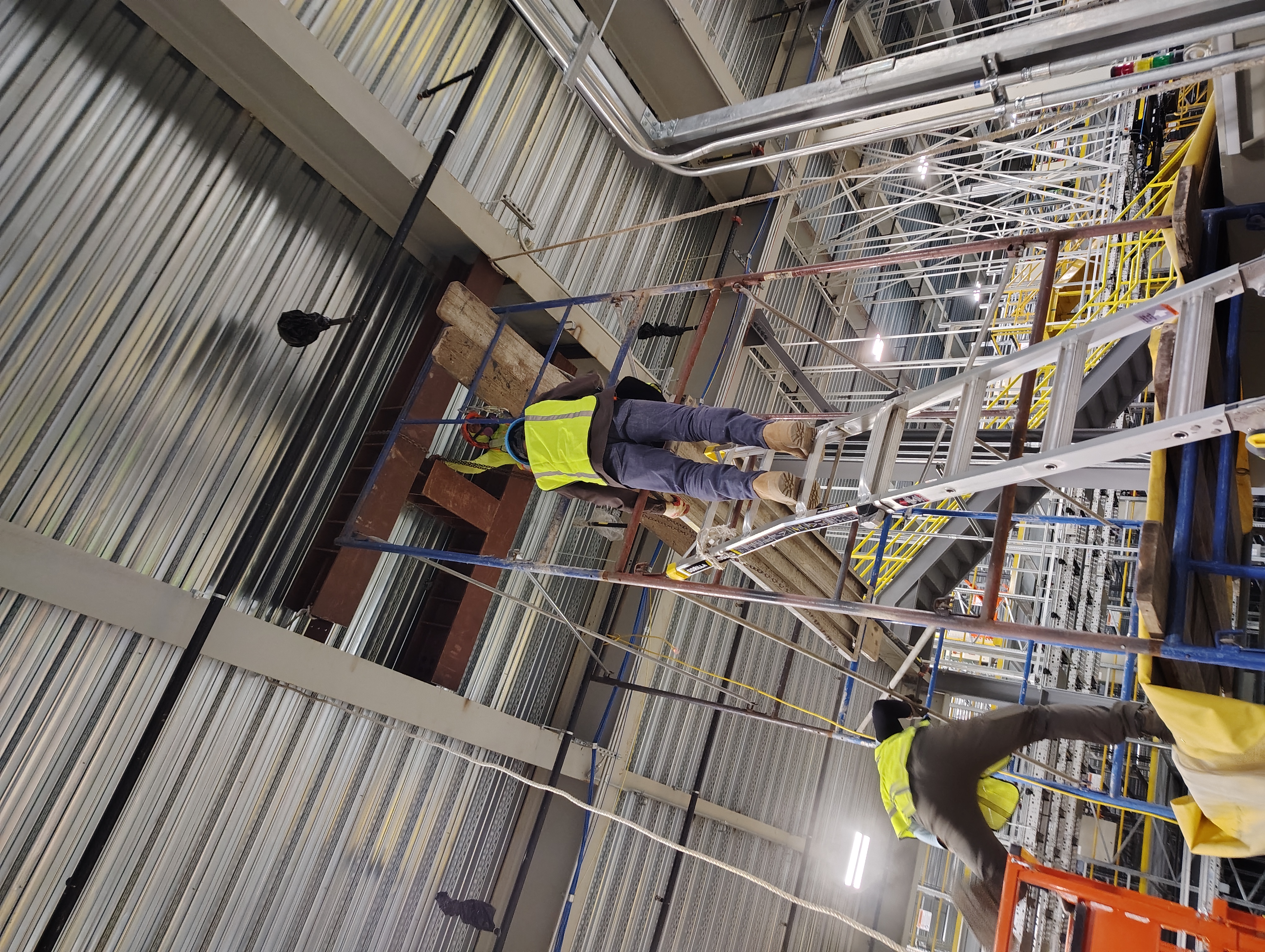 Crew working from scaffolding to install steel framing inside an industrial building