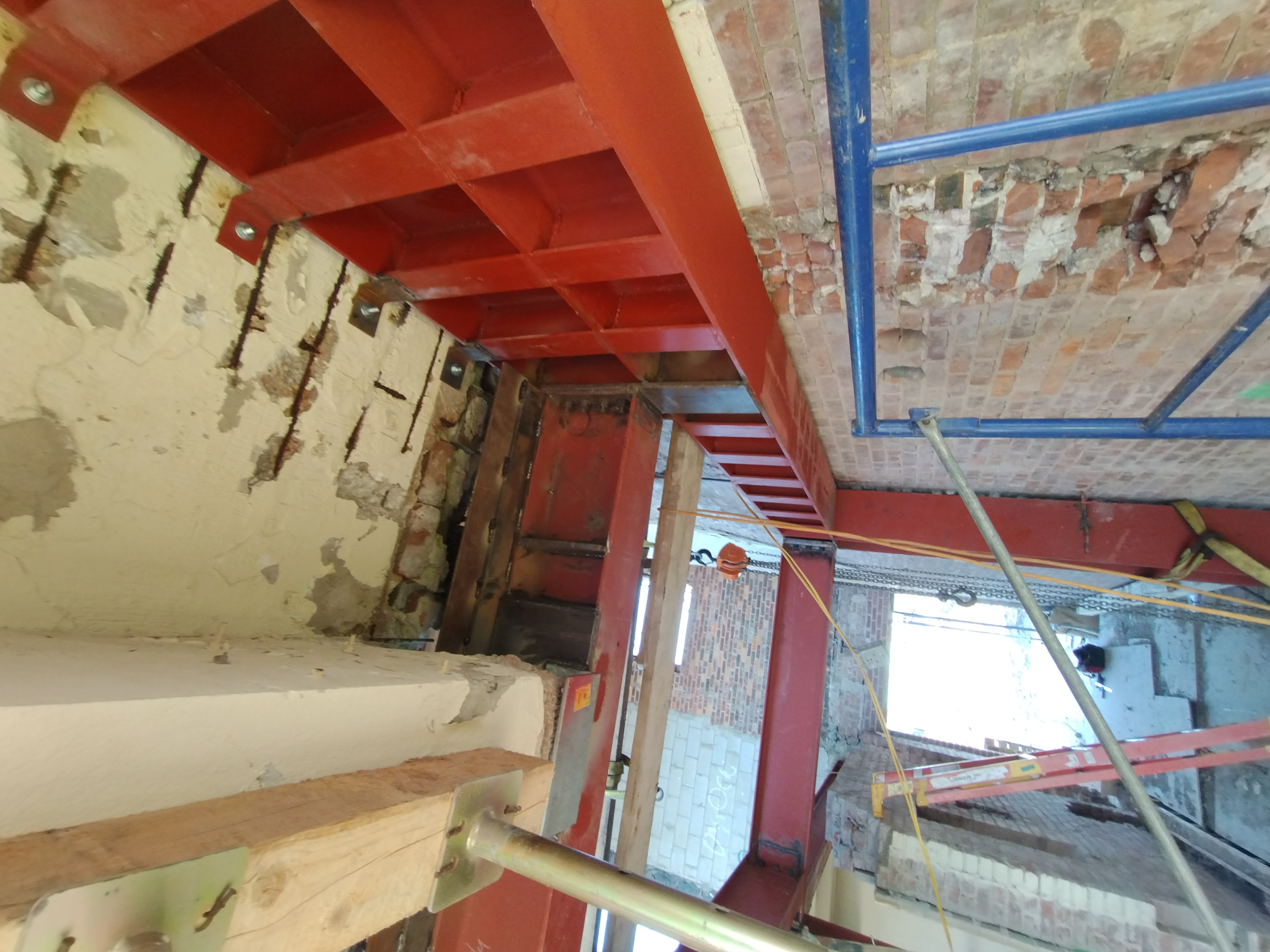 Red-primed steel beams with stiffener plates inside a masonry building