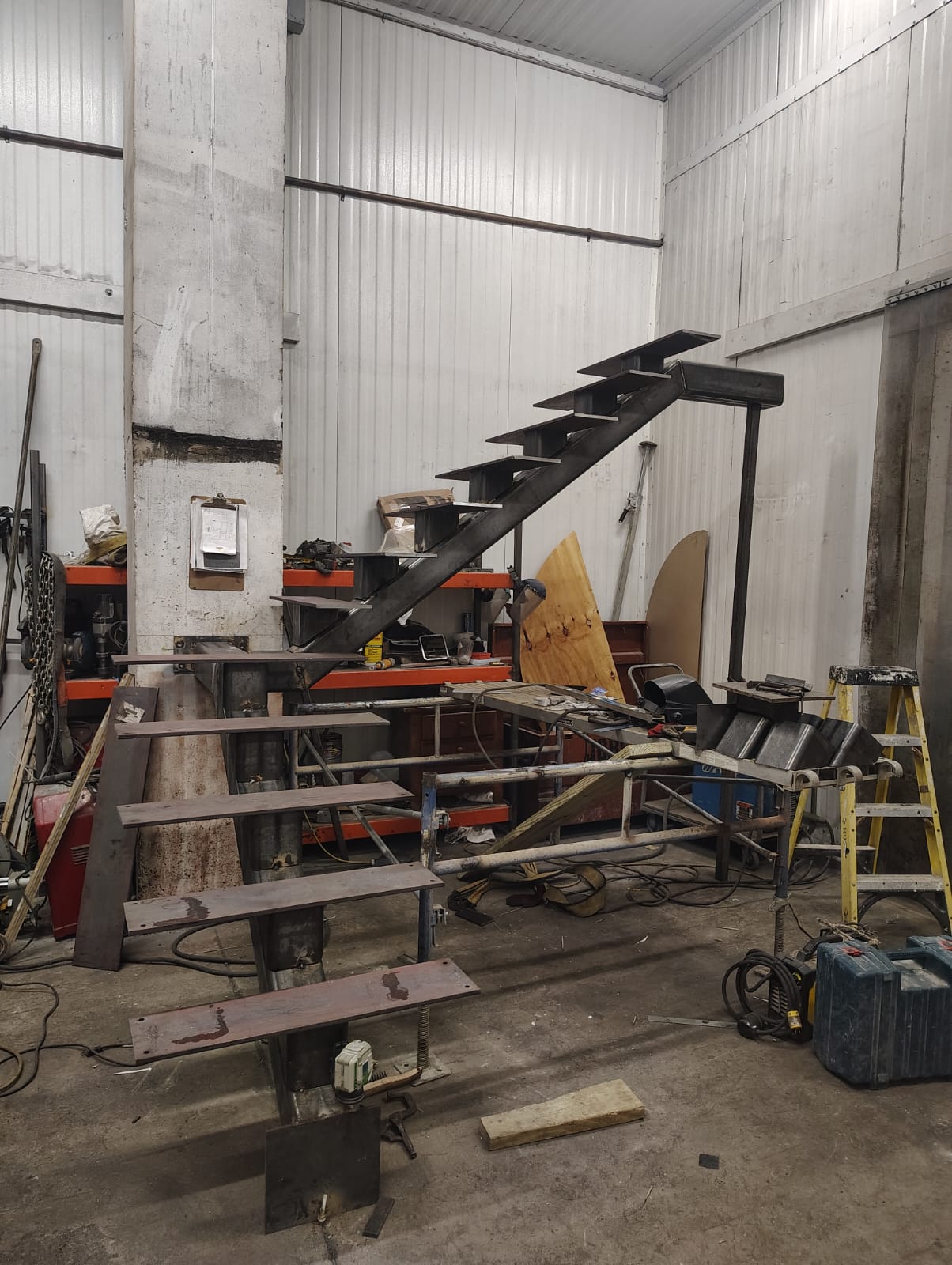 Steel stair frame with a central stringer and welded tread plates in the workshop