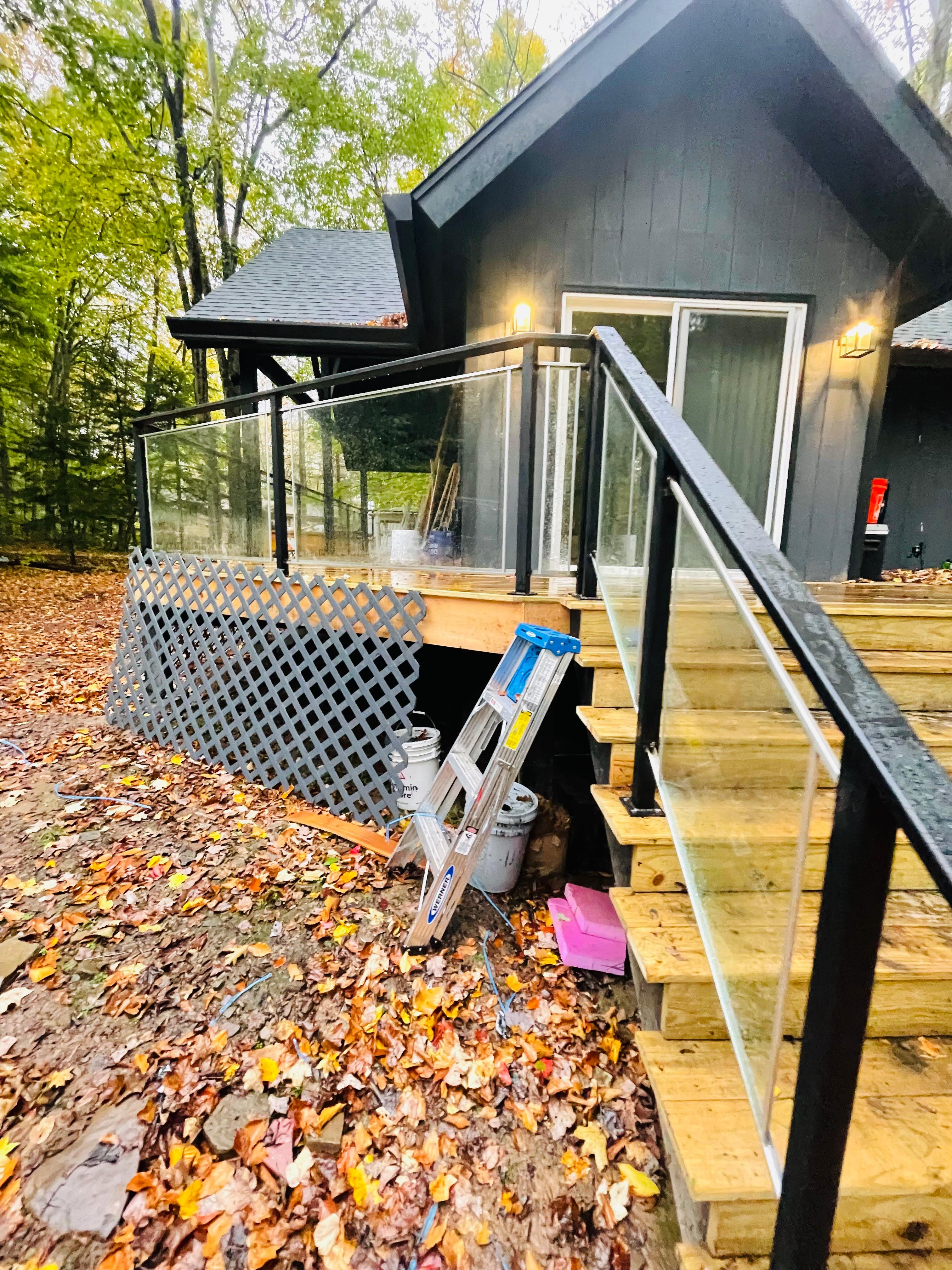 Black metal railing with clear glass panels along timber steps and a deck