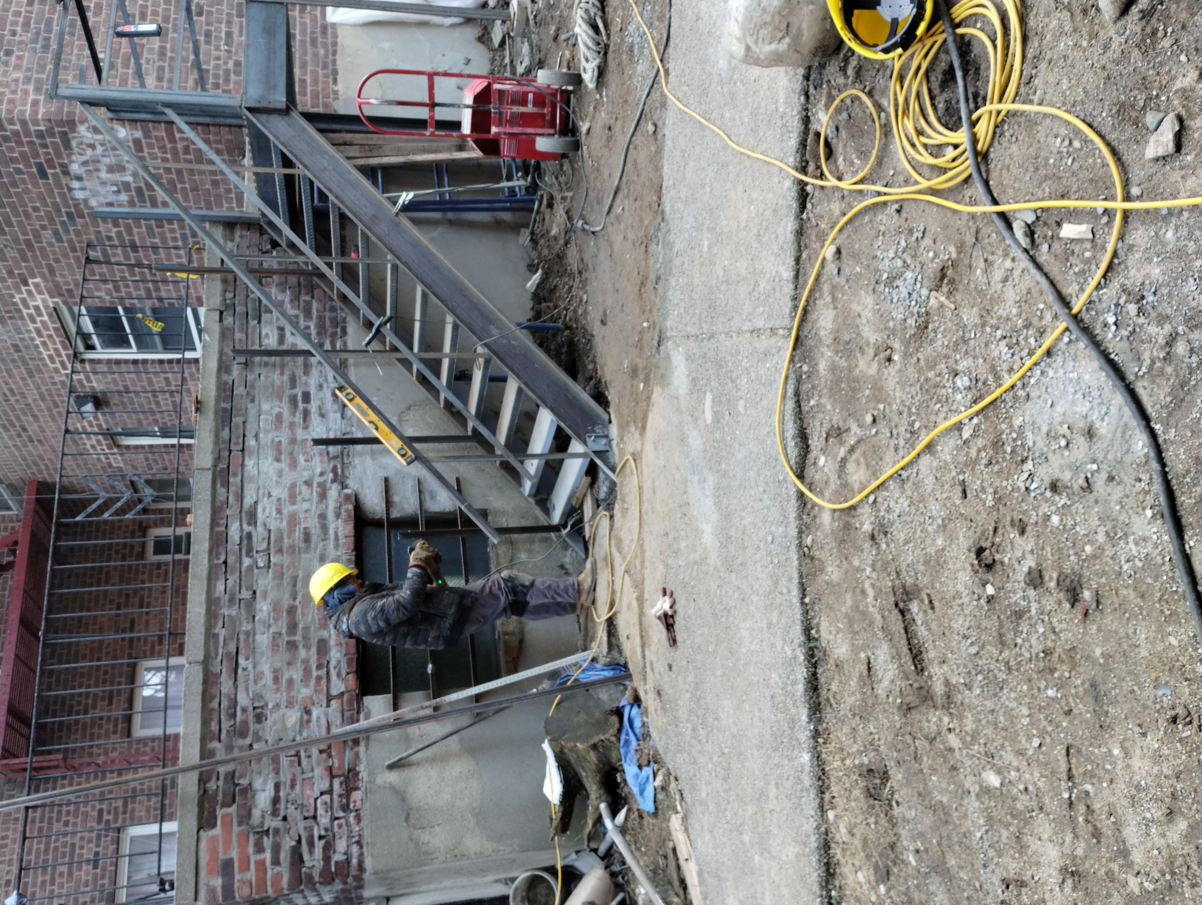 Steel exterior staircase and landing during installation beside a brick building