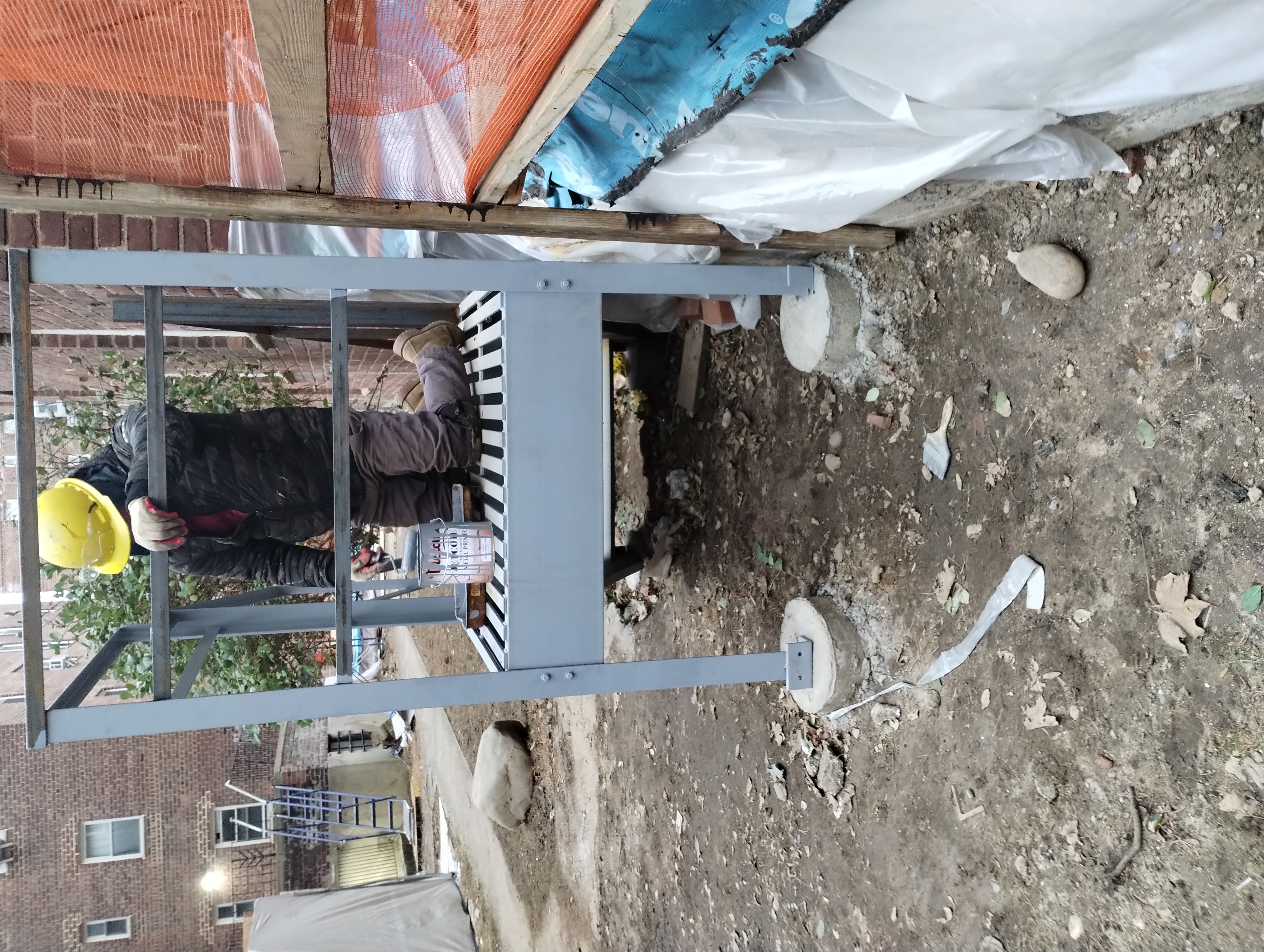 Worker applying a coating to a steel landing with railings