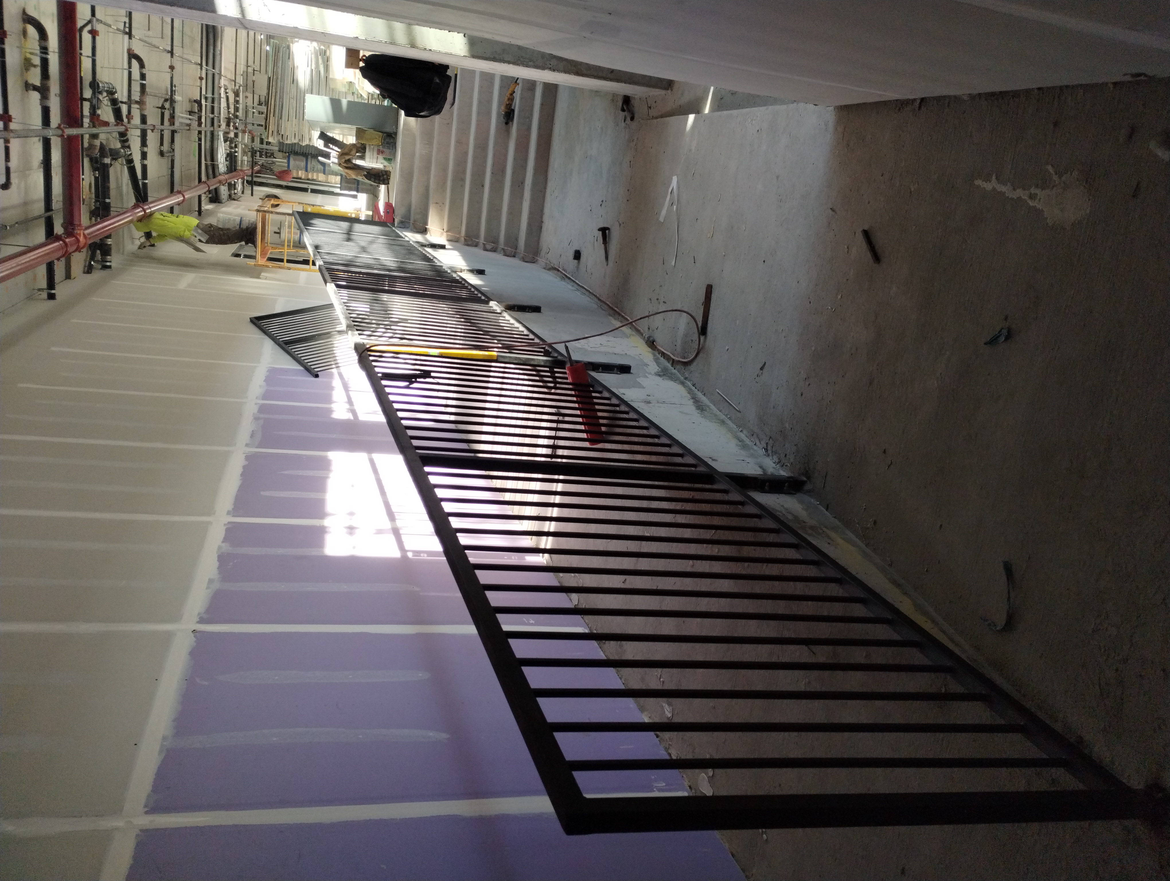 Long black steel guardrail beside an interior ramp during construction