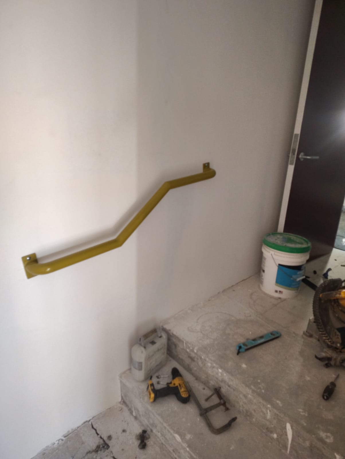 Angled wall-mounted metal handrail beside interior steps