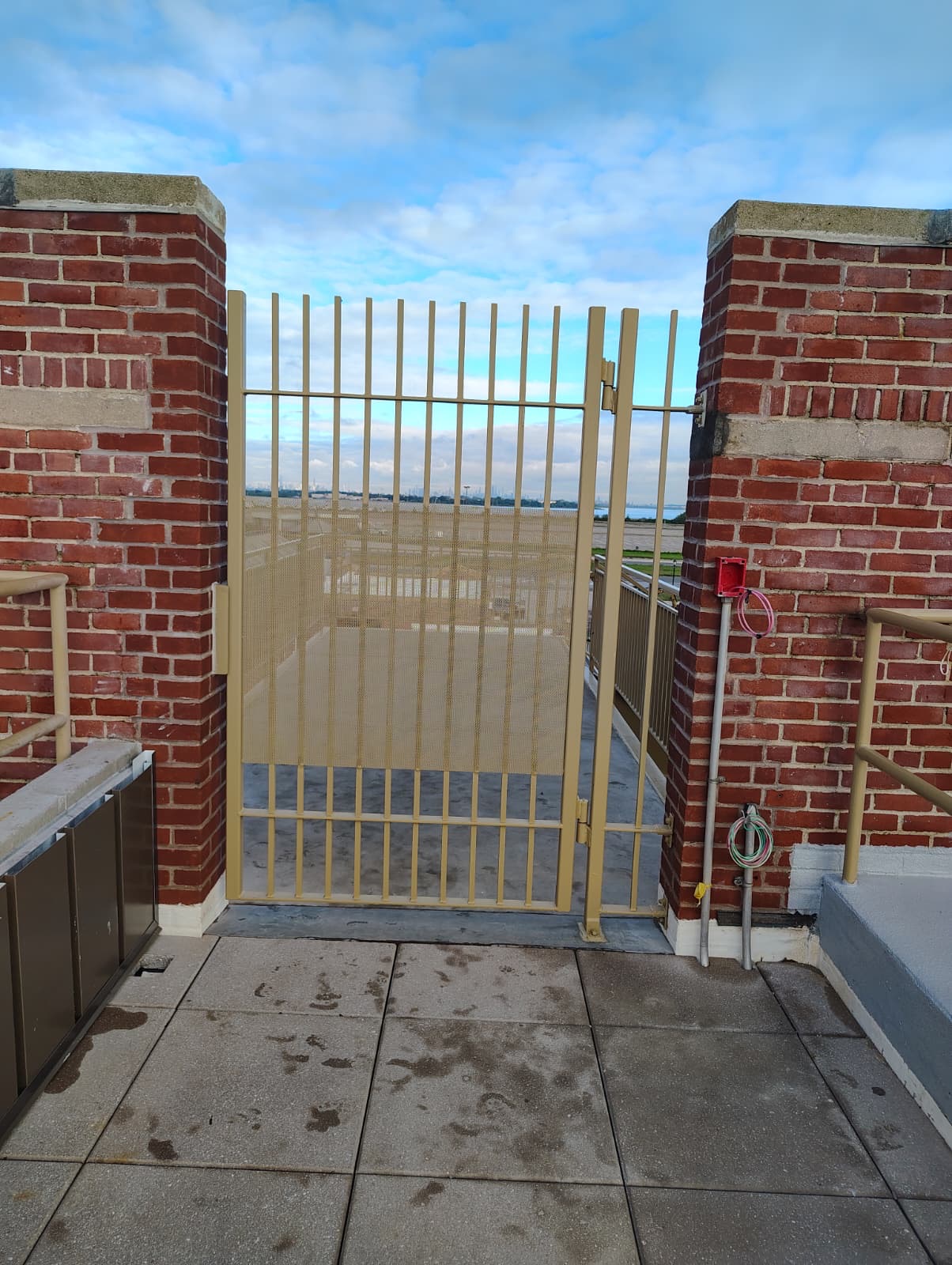 Painted rooftop gate and fixed side panel installed between brick piers