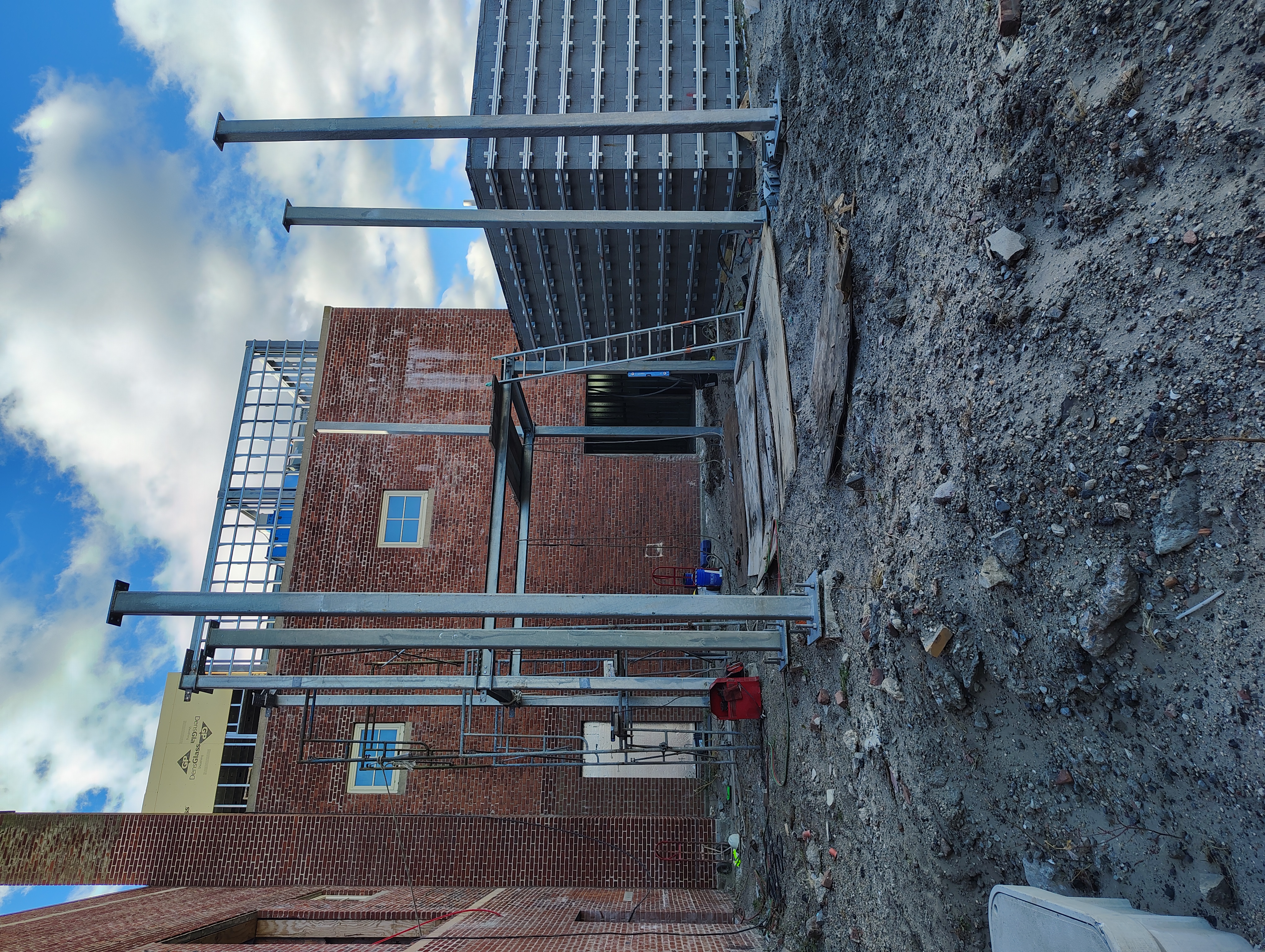 Tall steel columns and connecting beams beside a brick building