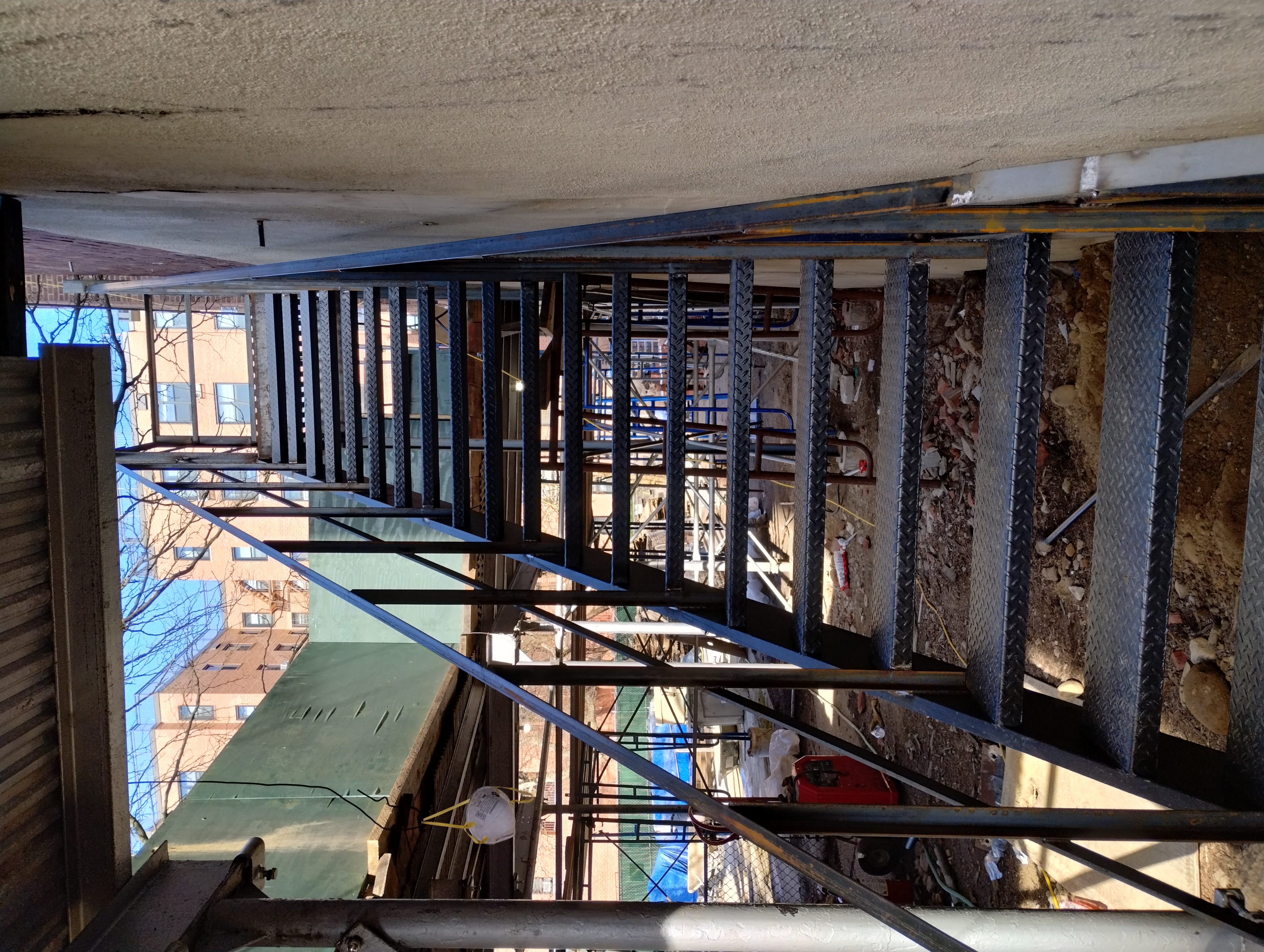 Exterior steel stairs with diamond-pattern treads, viewed from below