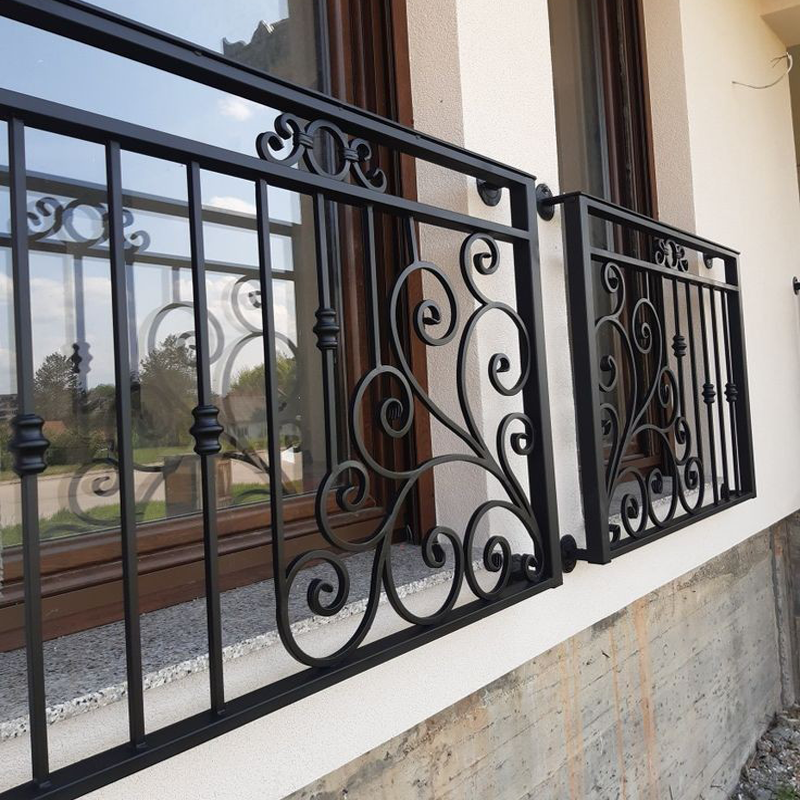 Black decorative steel railings with scroll details outside windows
