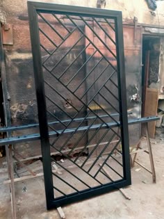 Tall black steel panel with geometric diagonal bars in a workshop
