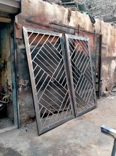 Unfinished double metal gate with diagonal geometric infill in a workshop