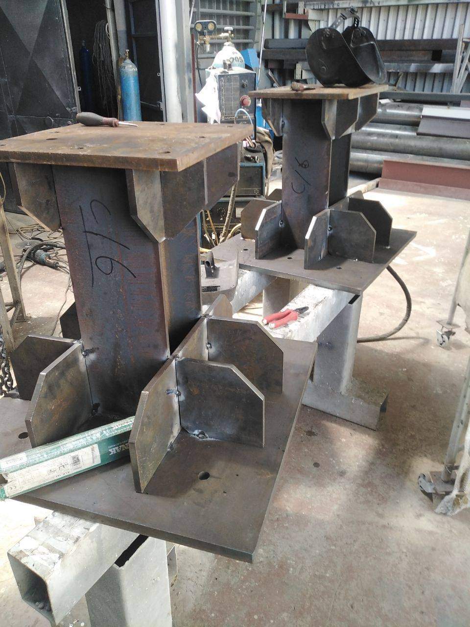 Two steel column assemblies with welded plates in a workshop