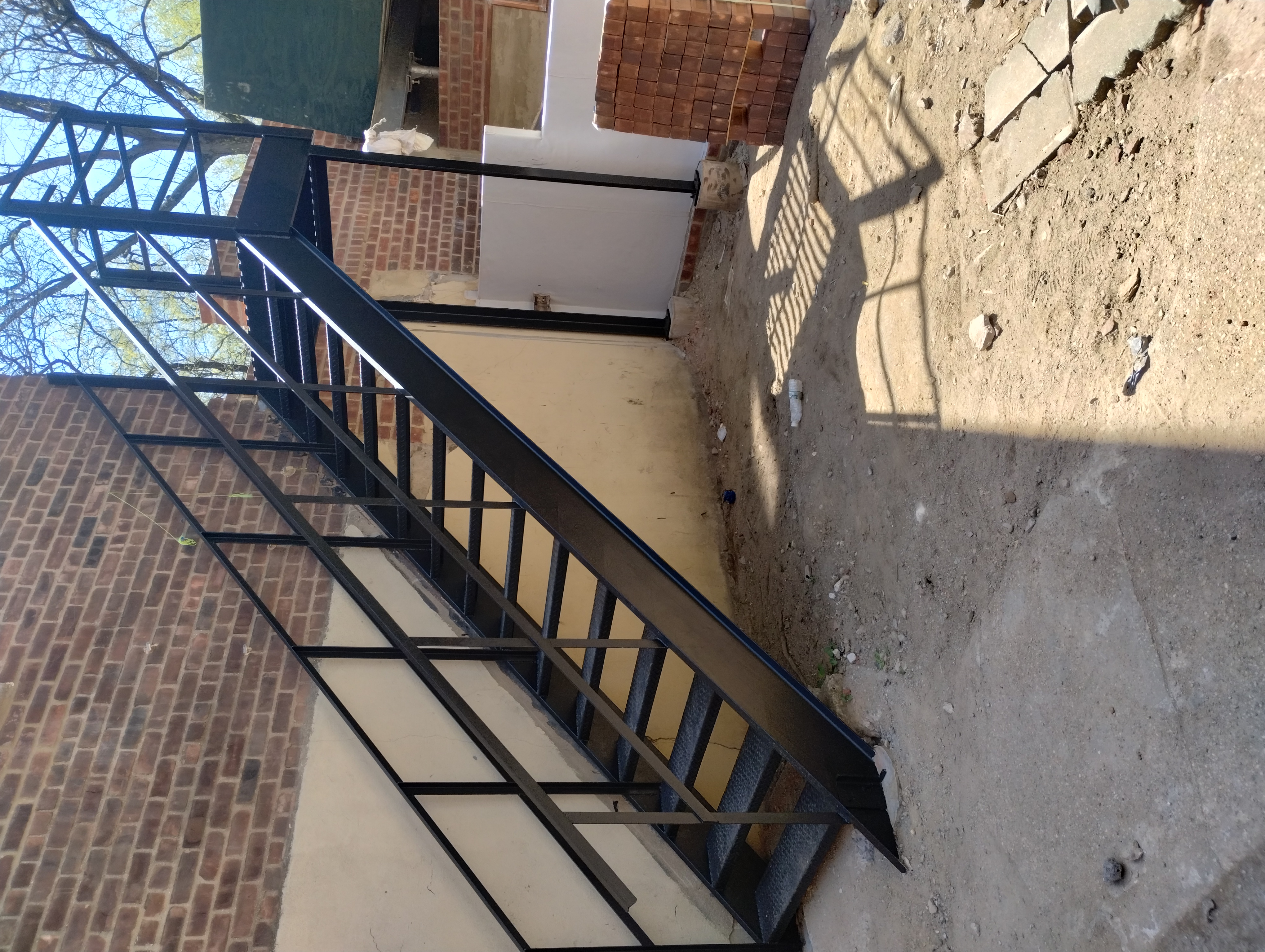 Black exterior steel staircase and landing beside a brick building