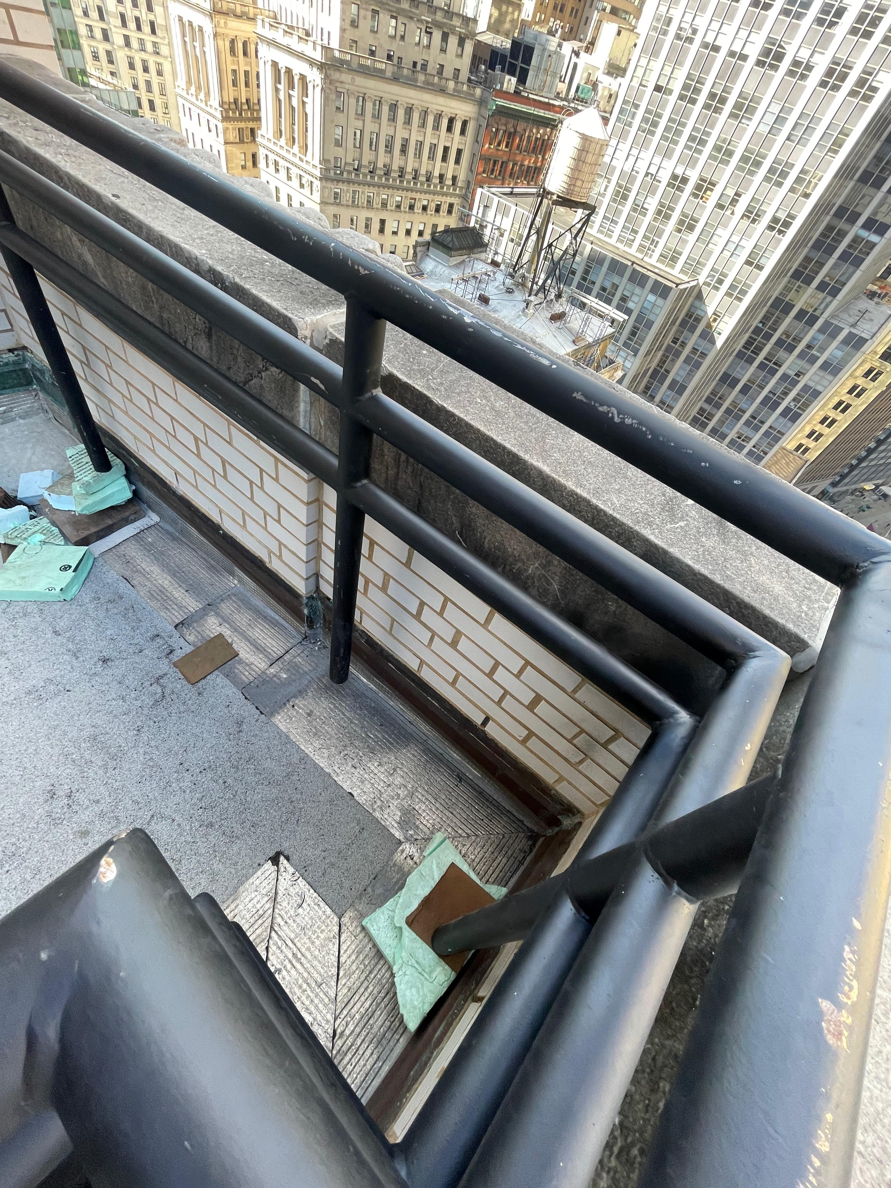 Black tubular metal railing at a rooftop parapet corner
