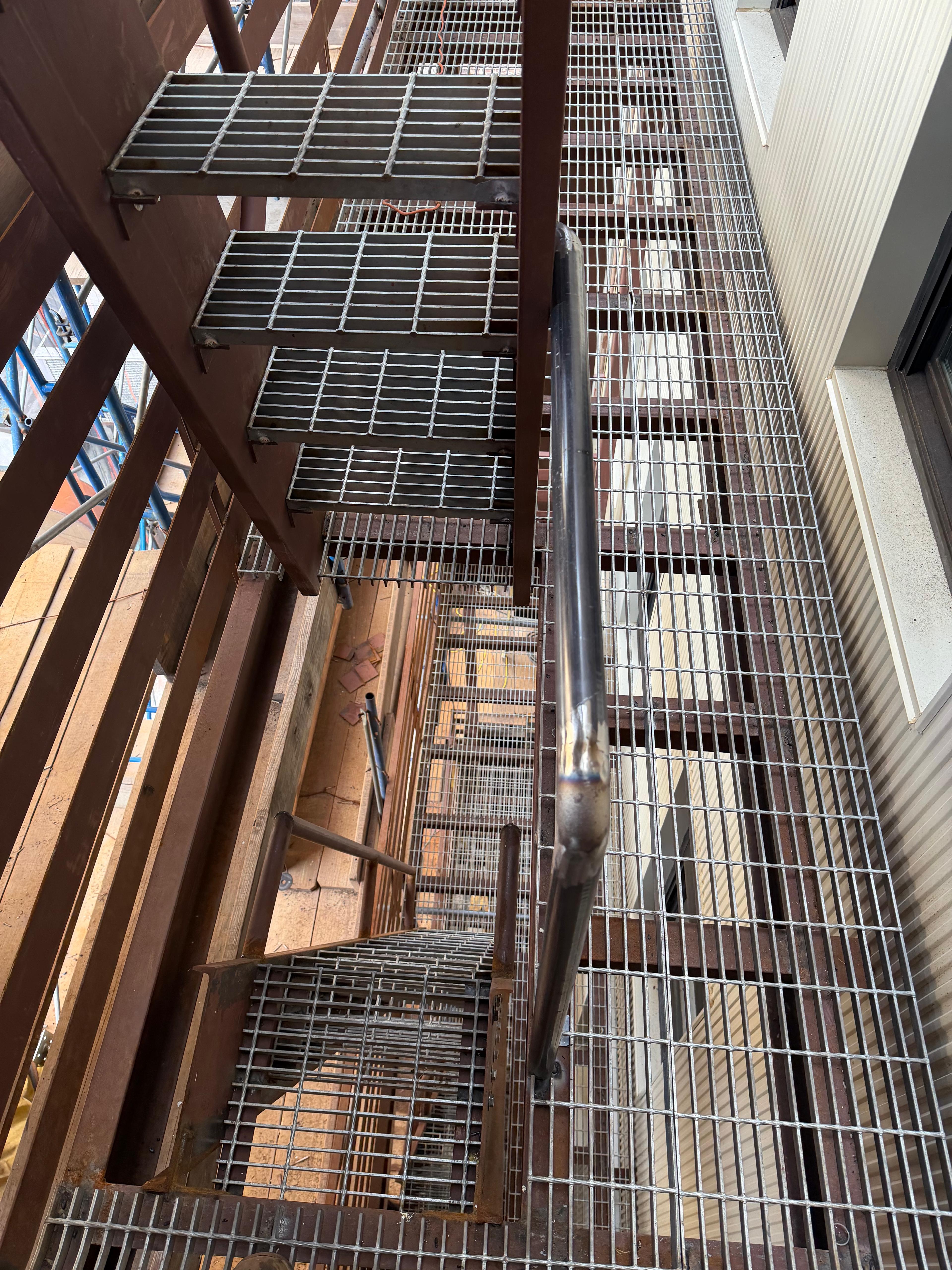 Steel bar grating treads and landings viewed down an exterior staircase