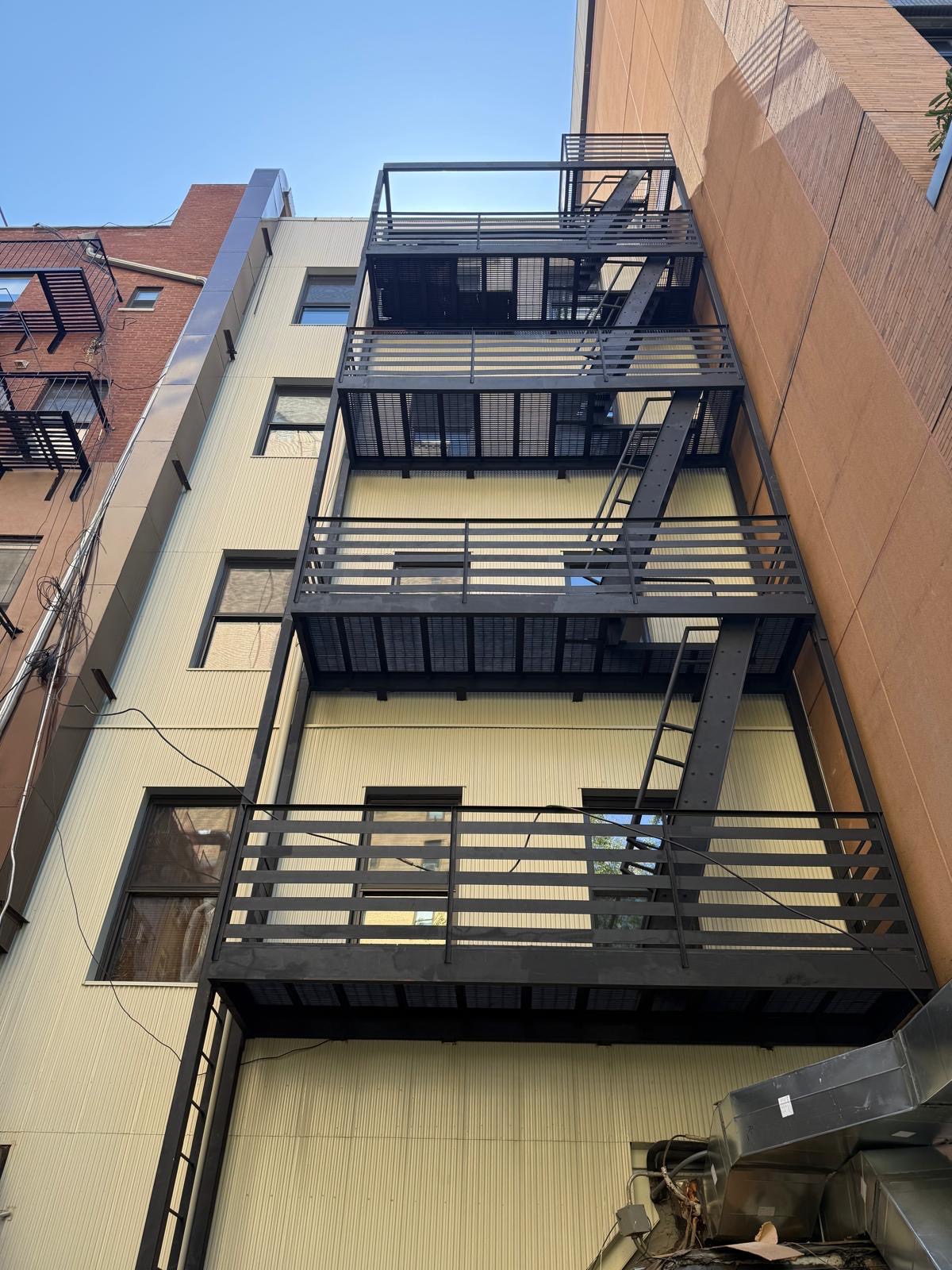 Full-height view of exterior steel stairs and stacked landings beside a building