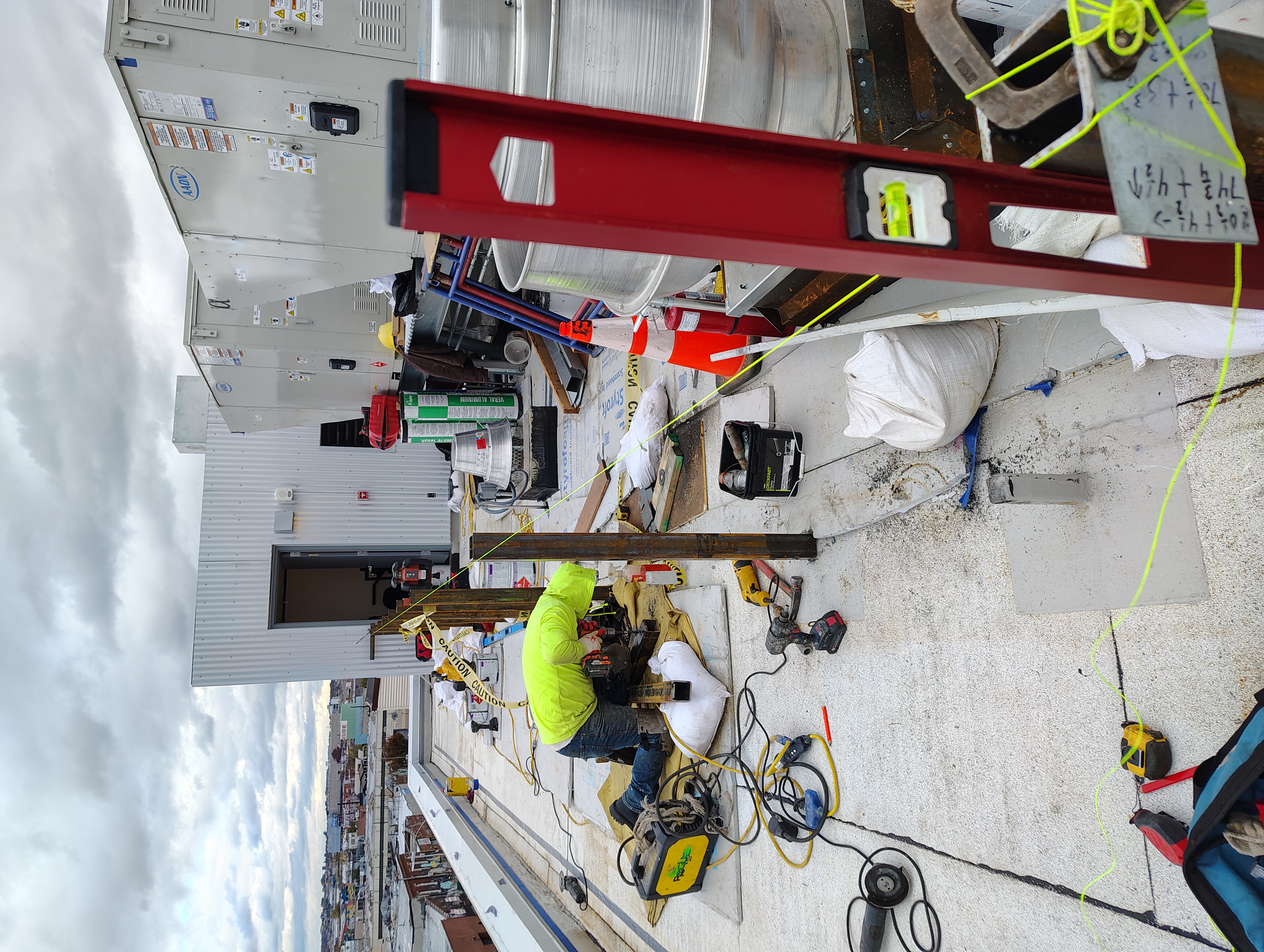 Worker fitting steel posts beside rooftop mechanical equipment