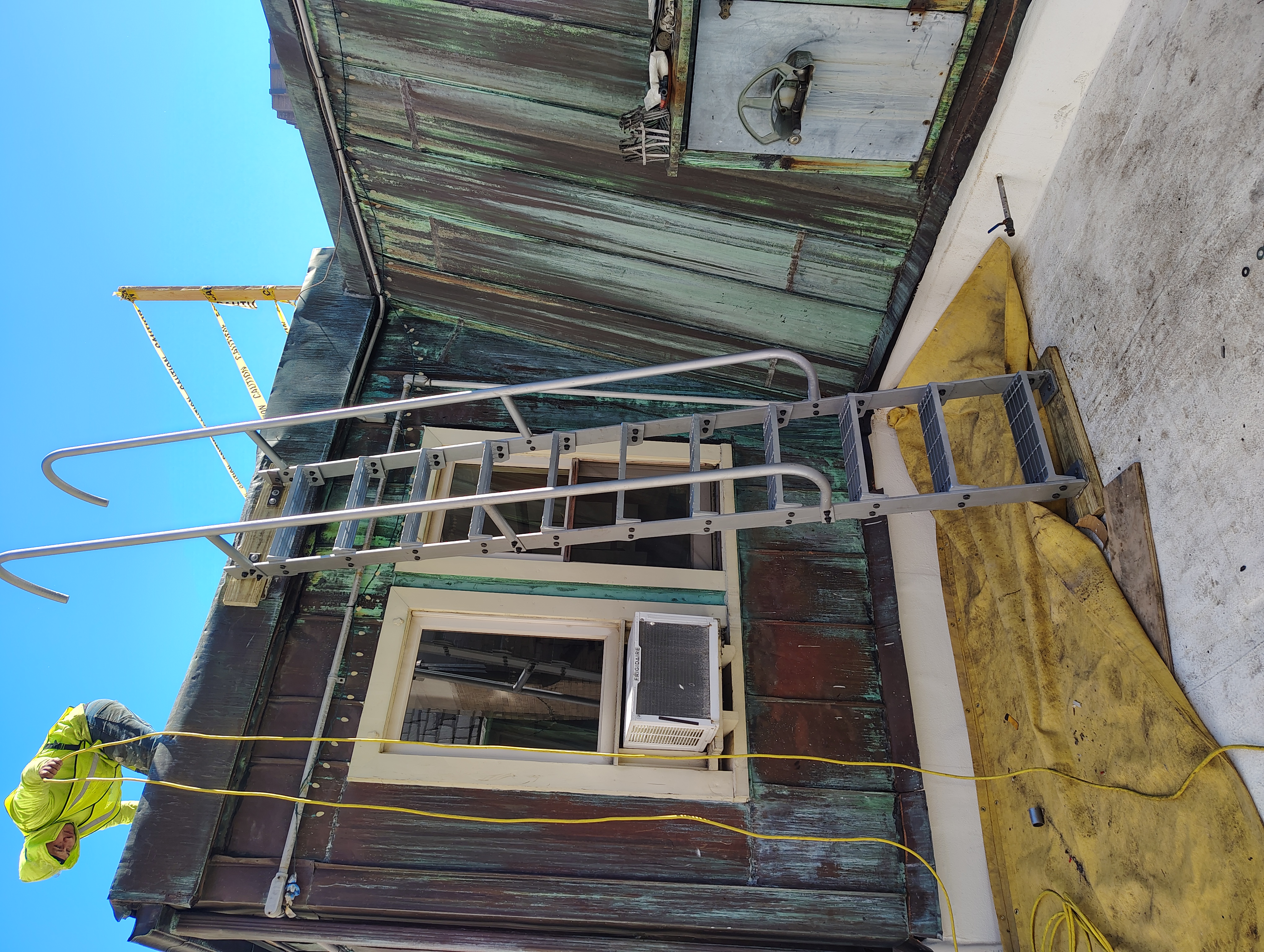 Steel roof access ladder with grating steps and curved handrails