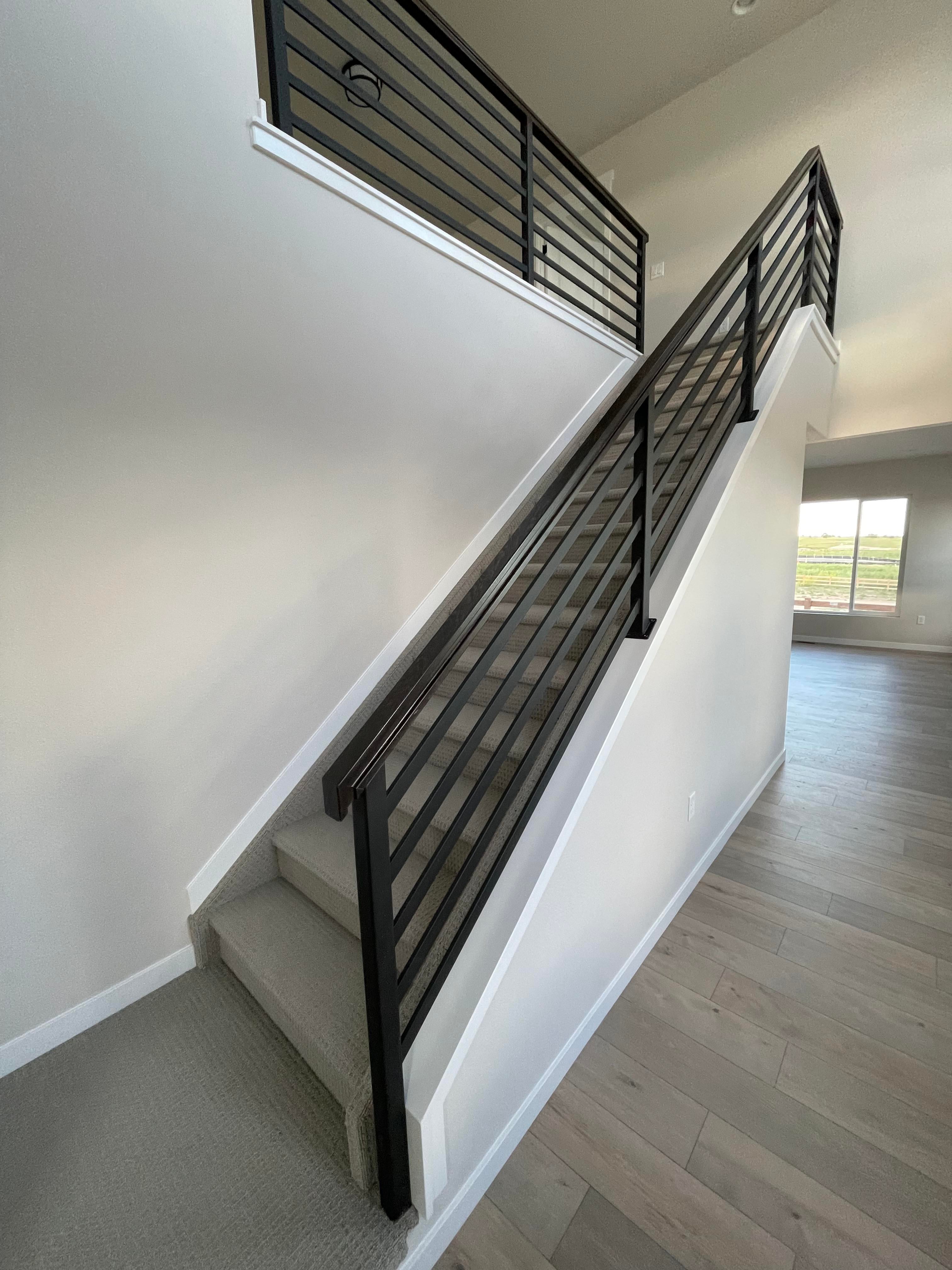 Black horizontal-bar stair and landing railings in a white interior