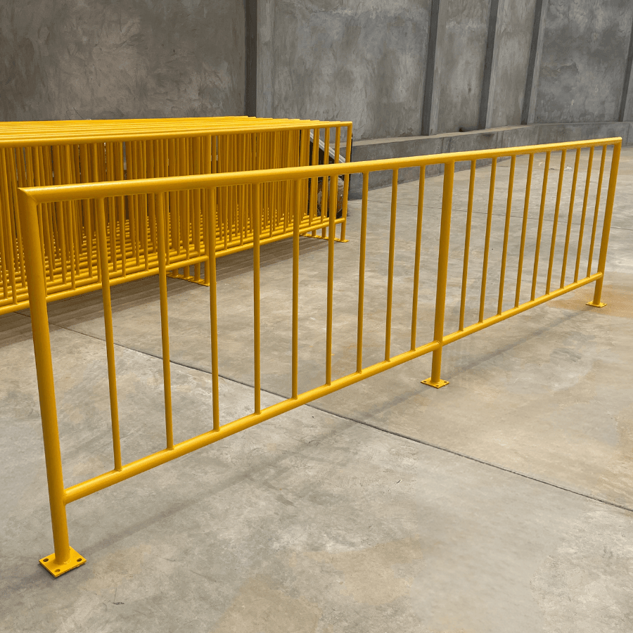 Yellow steel railing sections with vertical bars and mounting plates