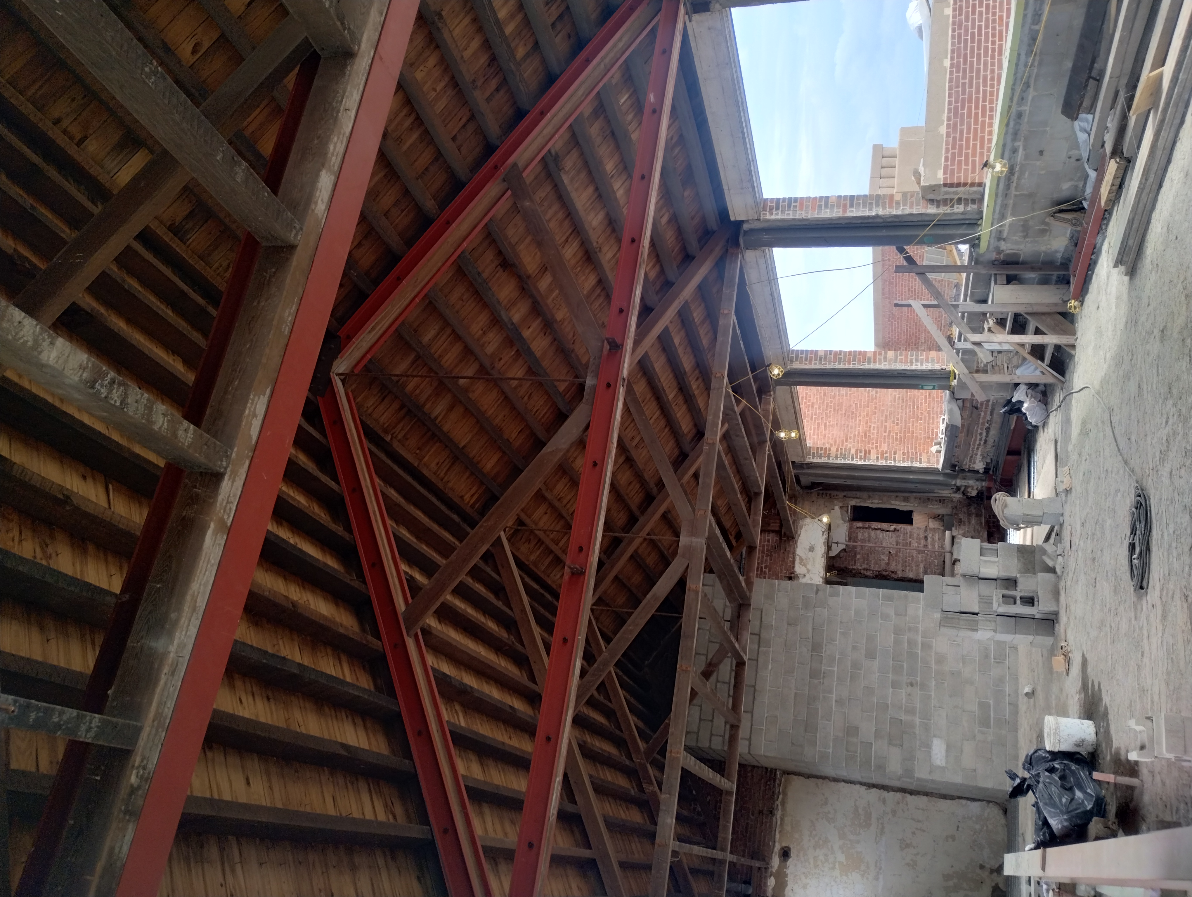 Red-primed steel reinforcing members fitted alongside existing timber roof trusses